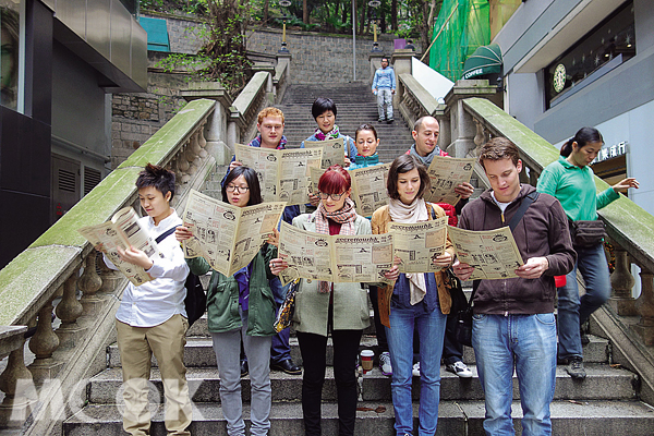 團友拿著Secret Tour Hong Kong印製的仿舊報紙傳單，走入香港老時光。（圖片提供／Secret Tour Hong Kong）