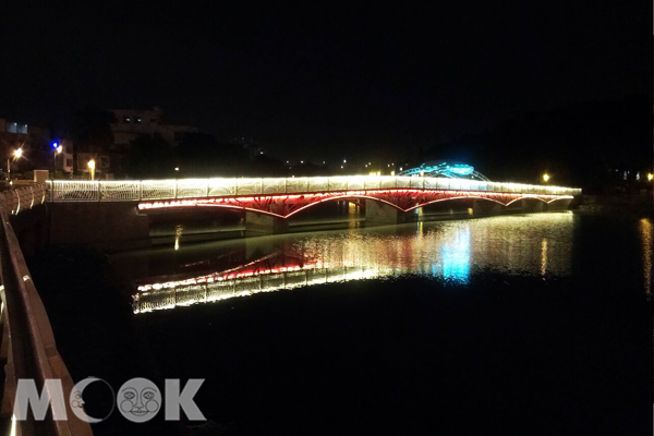 夜間燈火點亮金獅橋，水面映照光影搖曳。(圖片提供／高雄市觀光局）