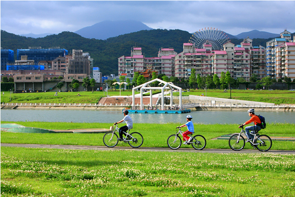 踩著腳踏車在河濱公園享受自然春光。(圖片來源／台灣觀光局）