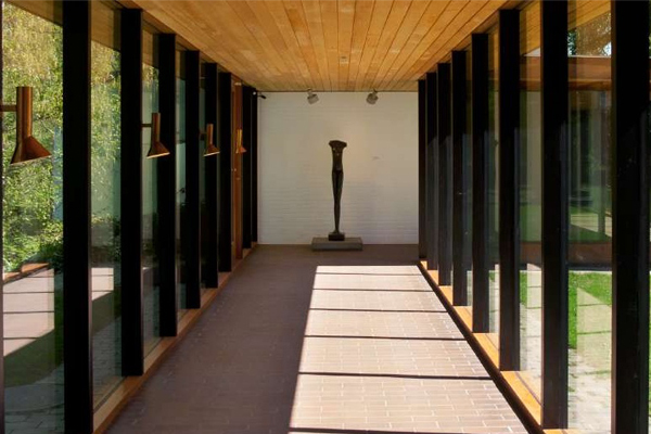 長形走廊，兩旁多是落地窗，畫作或雕塑作品即是背景。（圖片來源／louisiana）