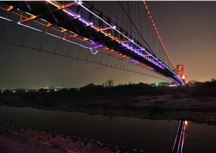 黑夜中，行嘉吊橋的霓虹燈特別顯著，猶如夜光珠鍊般在夜晚中閃爍。(圖片來源／嘉義市觀光局）