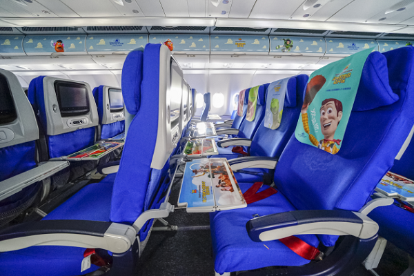 深藍色座椅搭配各個卡通角色的椅套、行李架及餐桌，就像是走進「玩具總動員」的世界一般。（圖／Shanghai Disneyland X China Eastern Airlines）