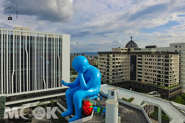藍色巨人在建築上方沉思