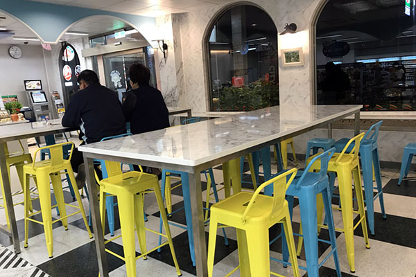 用餐區的大理石紋桌子和藍黃高腳椅，提升空間質感。(圖 / 7-11)