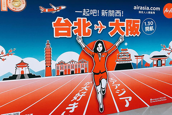 AirAsia於首航當日於桃園國際機場登機門舉辦首航儀式，還設置了大阪知地標「固力果Glico」跑跑人背板，邀請旅客在前往大阪之前先拍照打卡，十分有趣(圖／AirAsia)