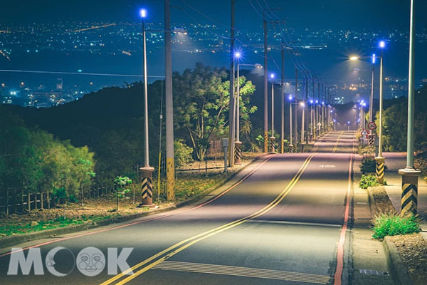 夜晚的藍色公路街燈亮起，寶藍色的光芒沿著筆直的道路延伸。 (圖／bb211019)
