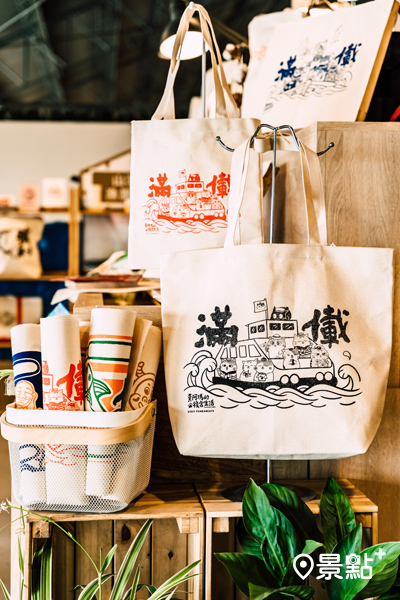 在棧貳庫的「山津塢」印製皇阿瑪圖案的托特包、兩用袋和餐墊，體驗高雄港區早期大漁文化。