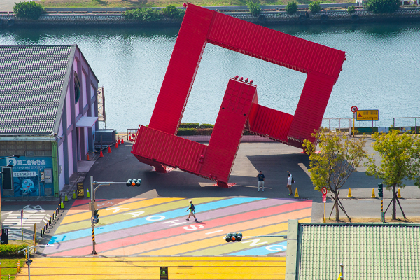 彩虹地景的後方是紅色貨櫃裝置藝術「巨人的積木」。（圖／高雄市政府）