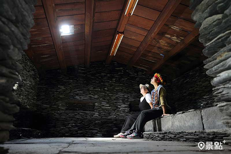 坐在石板屋裡，抬頭望著陽光灑落，彷彿回到萬山的舊時光。